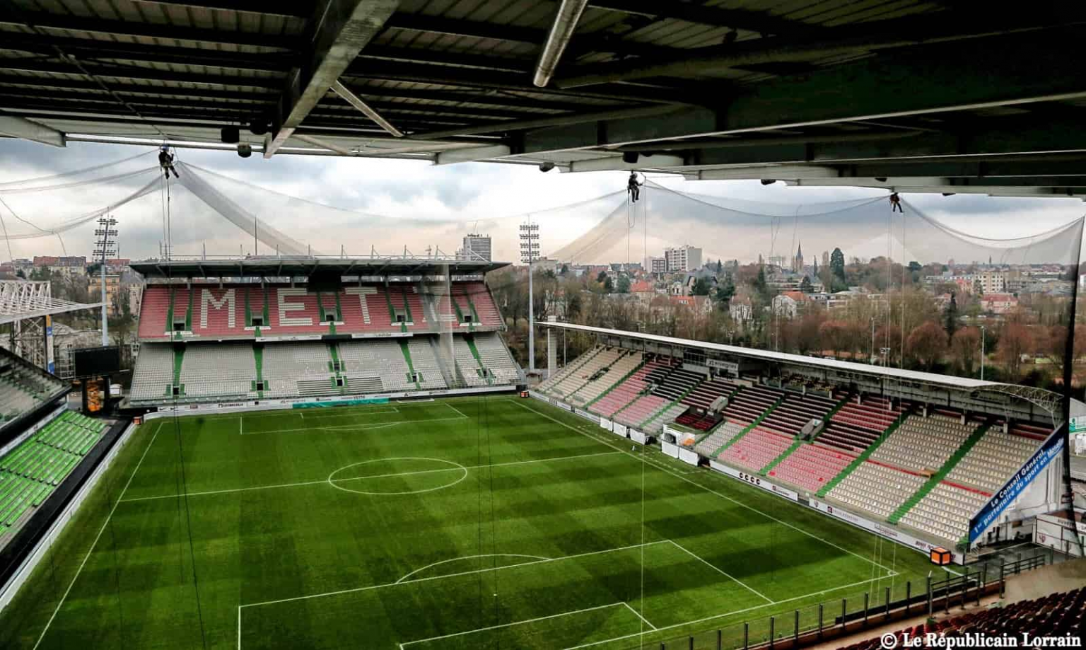 Ouvriers qui installent un filet anti pigeon dans un stade